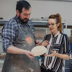 Two people working on decorating and glazing ceramics